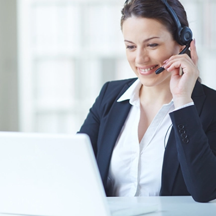 Eine Frau mit Headset sitzt an einem Laptop