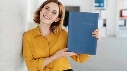 Eine glückliche Frau hält eine Mappe in der Hand 