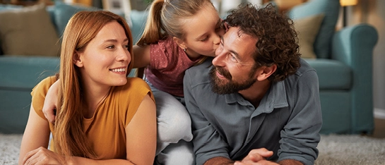 glückliche Familie mit Kind liegt auf Teppich vor Couch