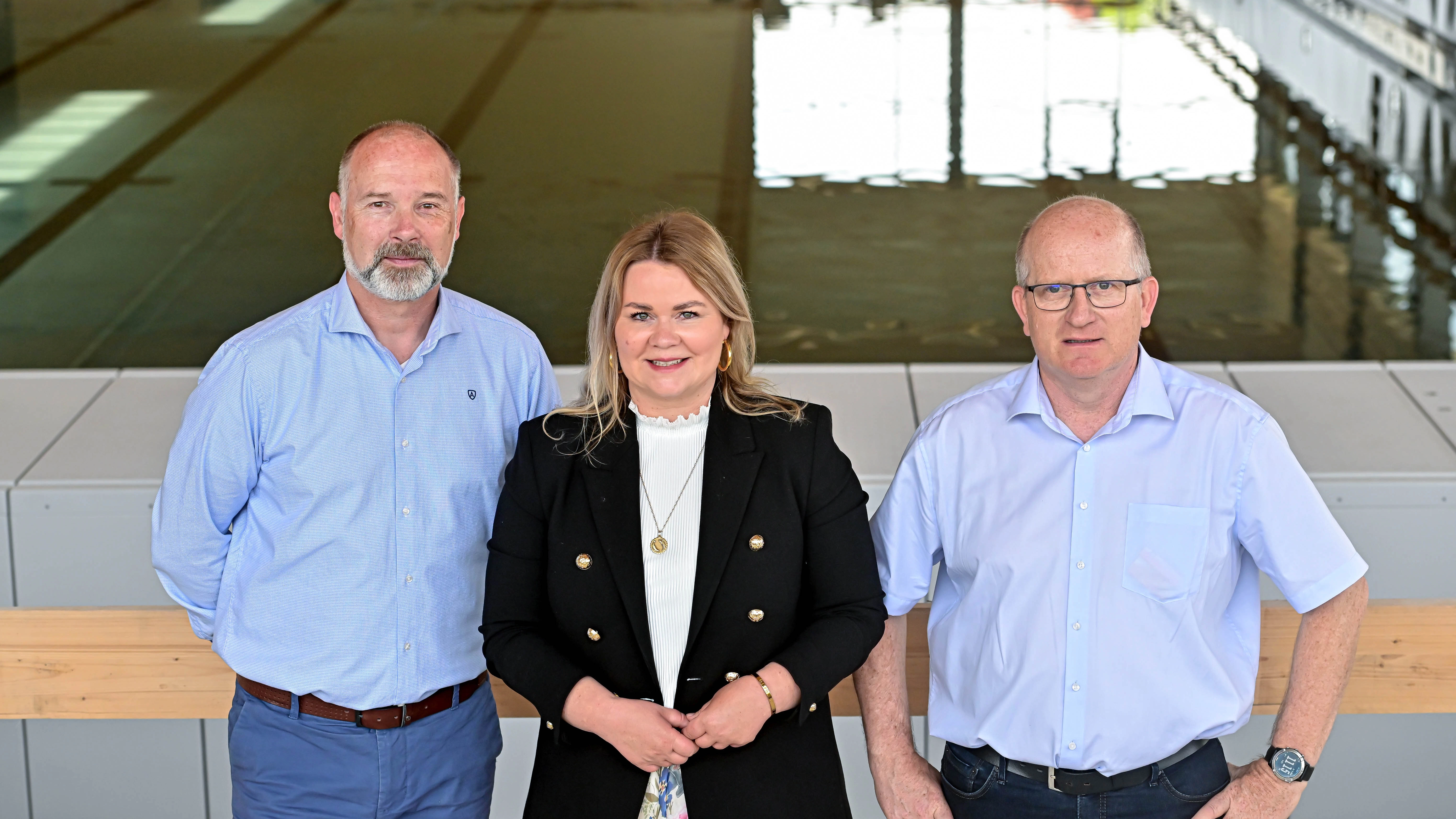 Drei Personen stehen in der neuen Sportschwimmhalle
