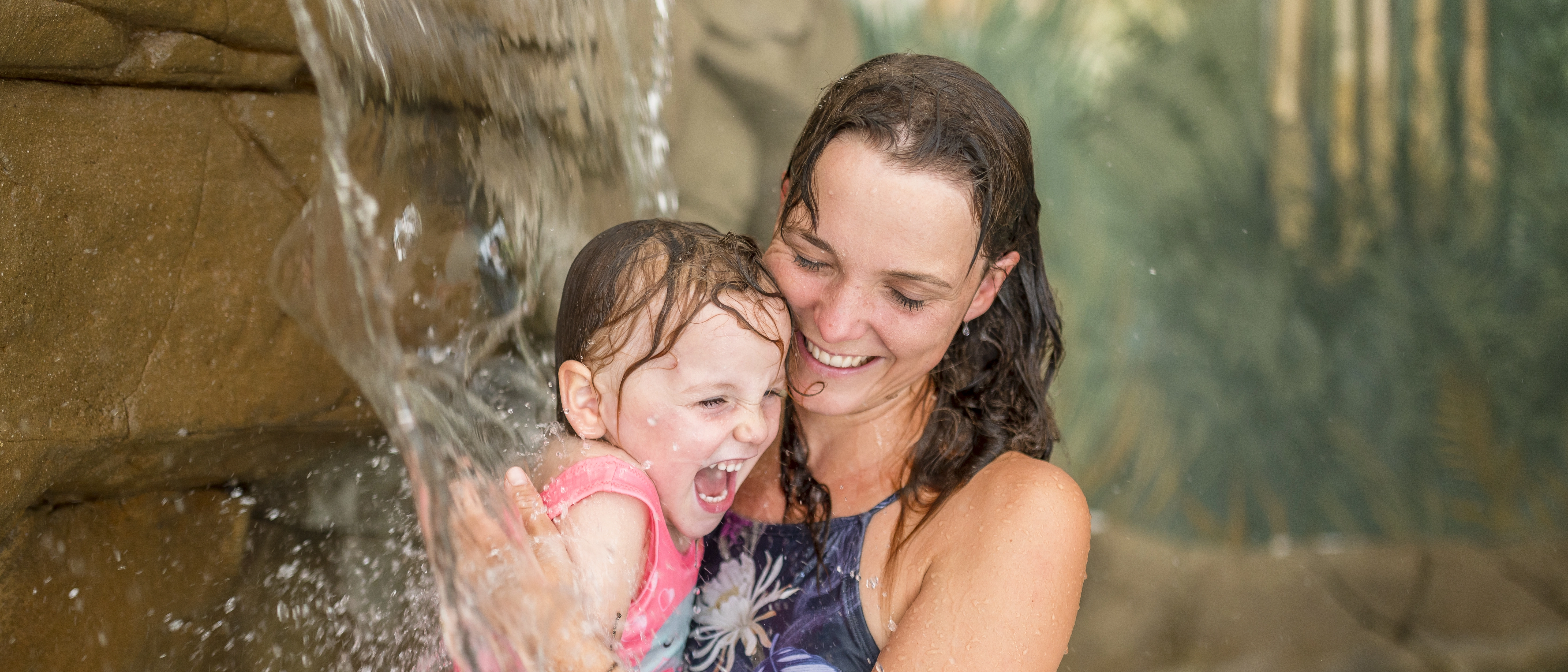 Eine Frau und ein Kind unter einem Wasserfall im GalaxSea