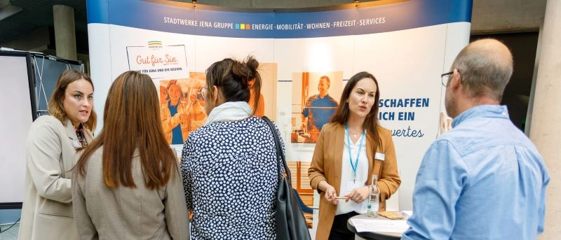 Personen stehen an einem Messestand