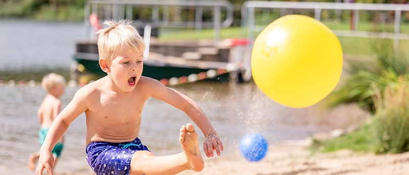 Ein Kind spielt mit einem Ball am Schleichersee
