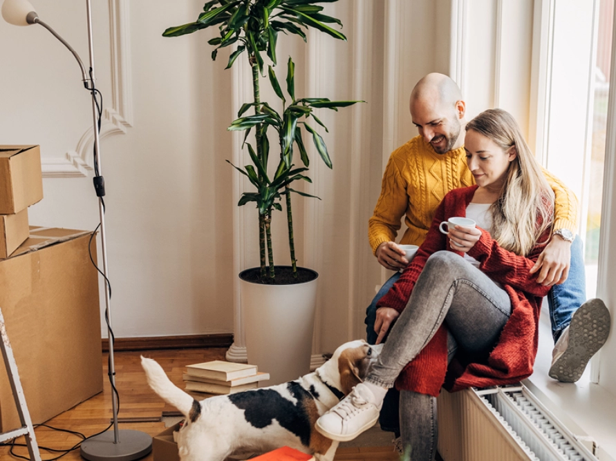Zwei Personen sitzen auf einer Heizung und blicken auf einen Hund Zwei Personen sitzen auf einer Heizung und blicken auf einen Hund